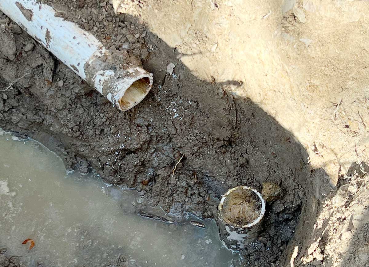 Excavated broken underground PVC water line awaiting repair